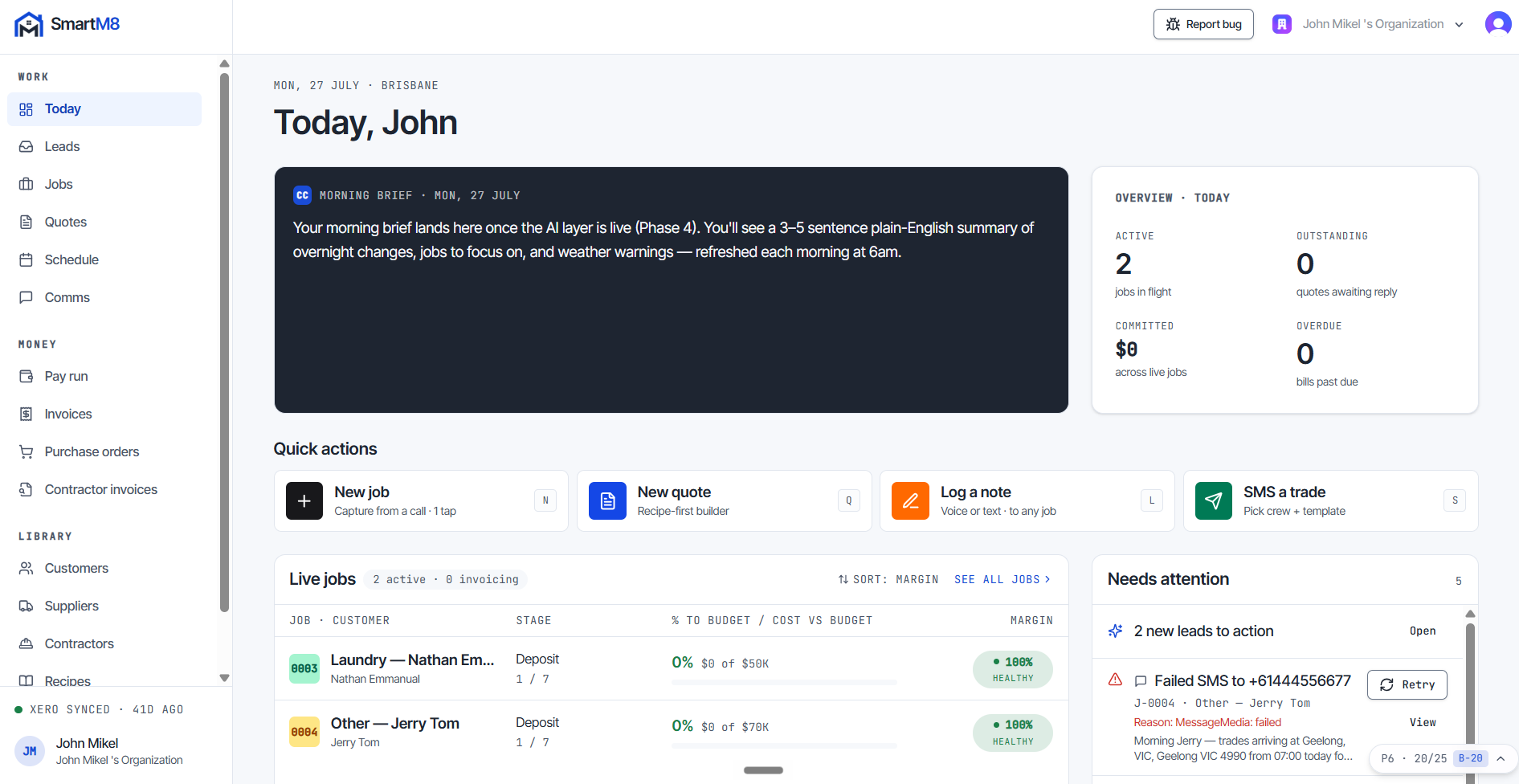 The SmartM8 Today dashboard. A left navigation rail groups the modules under Work, Money and Library. The main column opens with a morning-brief panel, then an overview strip counting jobs in flight, quotes awaiting reply, cost committed across live jobs and bills past due. Below it sit quick actions for starting a job or quote, logging a note and texting a trade, a live-jobs table showing the stage, percentage to budget and margin health of each job, and a needs-attention list of items to action.